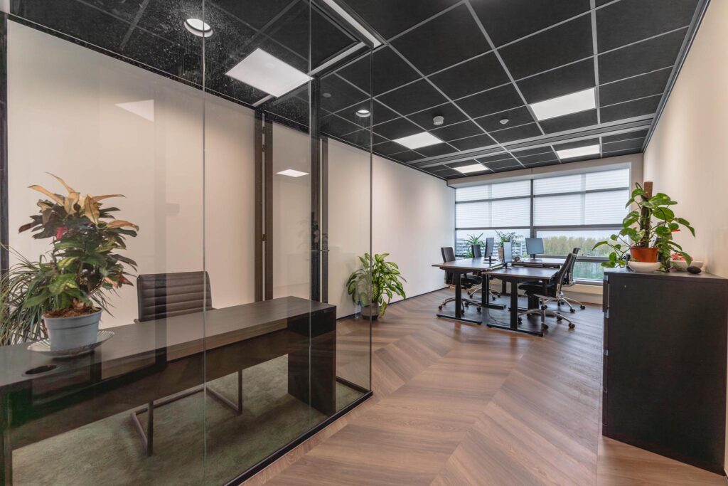 Modern office space at Joop Geesinkweg with glass-walled meeting room, desks, and indoor plants.